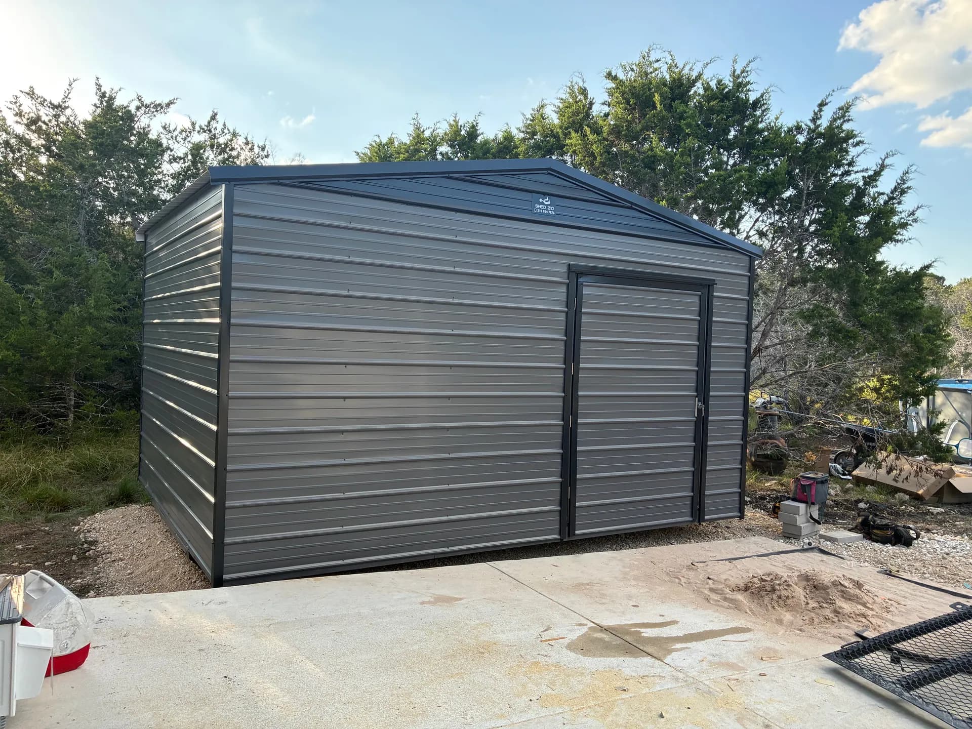 Front three-quarter view of a gray 12x16x9 utility shed with an extra-wide door and dark trim in Boerne, TX