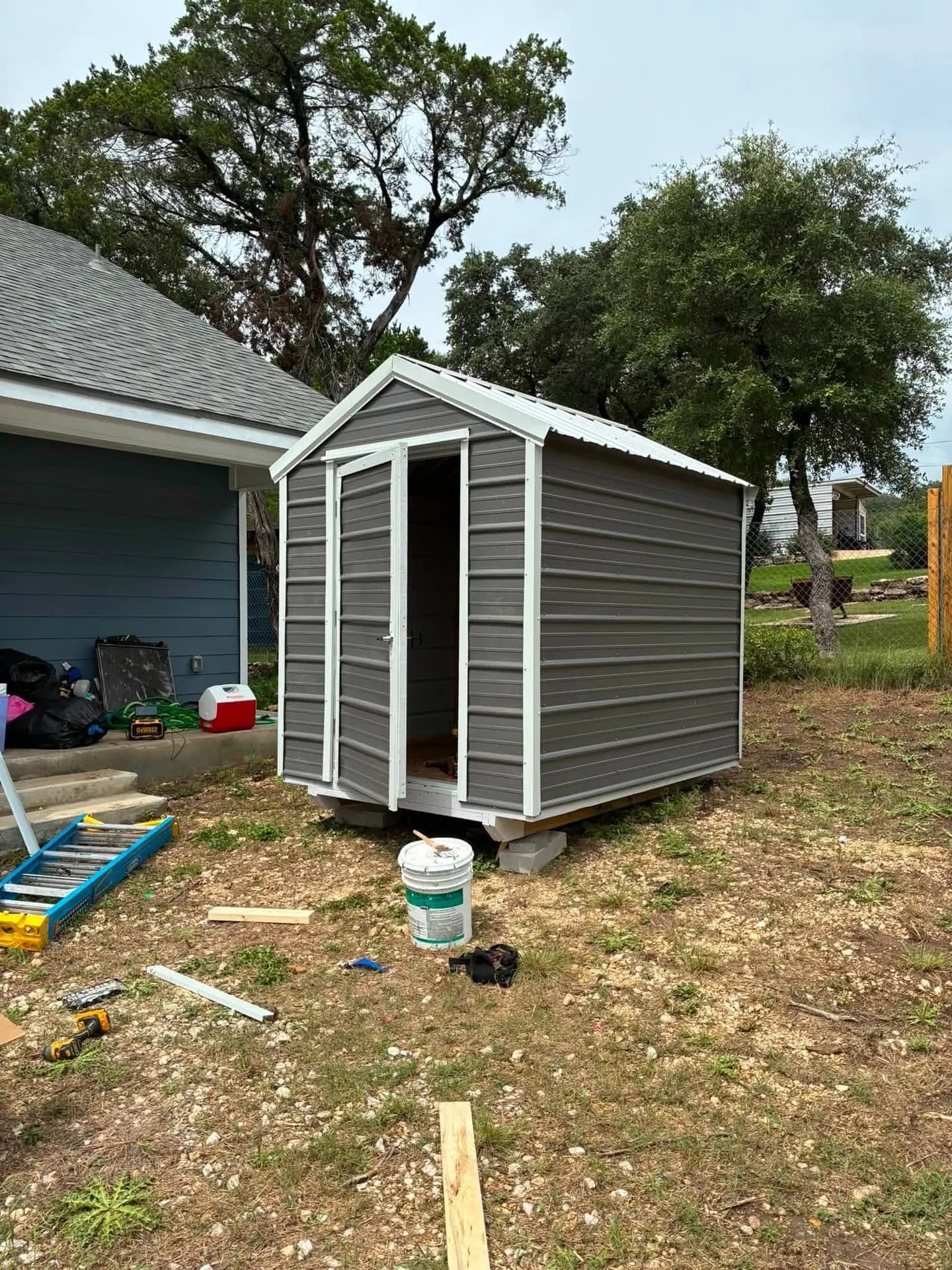 Finished charcoal metal shed with walk-in door open showing interior, on-site build in Lakehills, TX