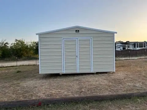 Straight-on view of the completed 16x20x9 Side Utility shed with light tan metal siding, white trim, and closed double doors in Luling.
