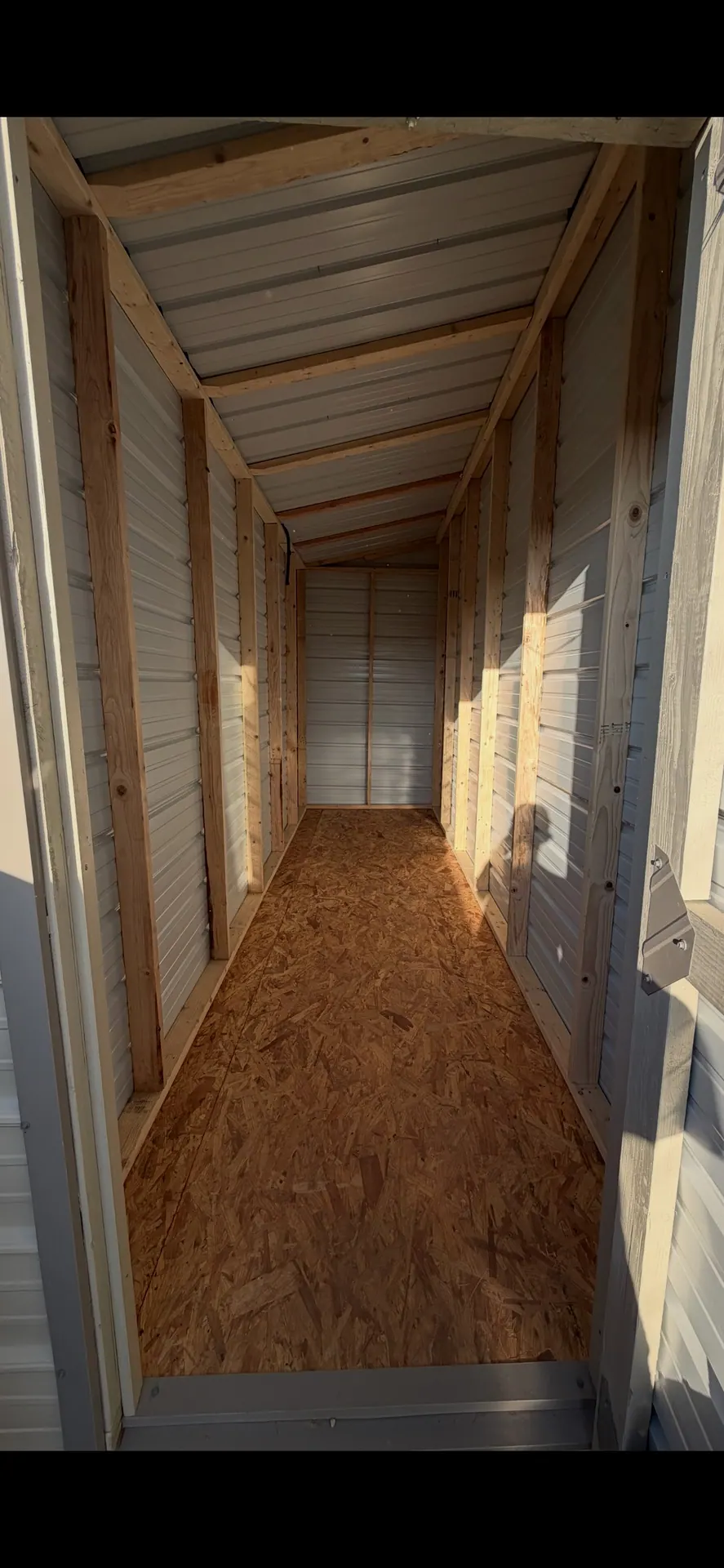Interior of the 6x16 shed showing exposed wood framing, metal wall panels, single-slope roof, and wood floor