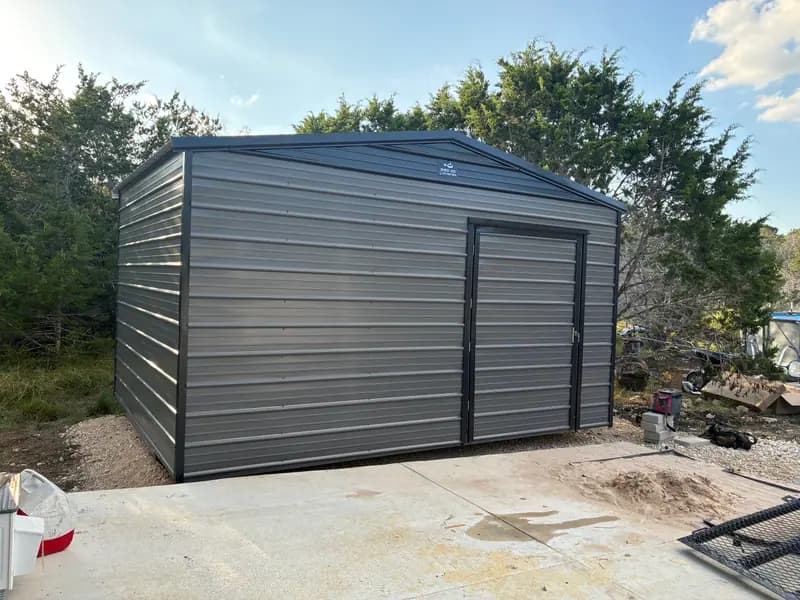 Front three-quarter view of a gray 12x16x9 utility shed with an extra-wide door and dark trim in Boerne, TX