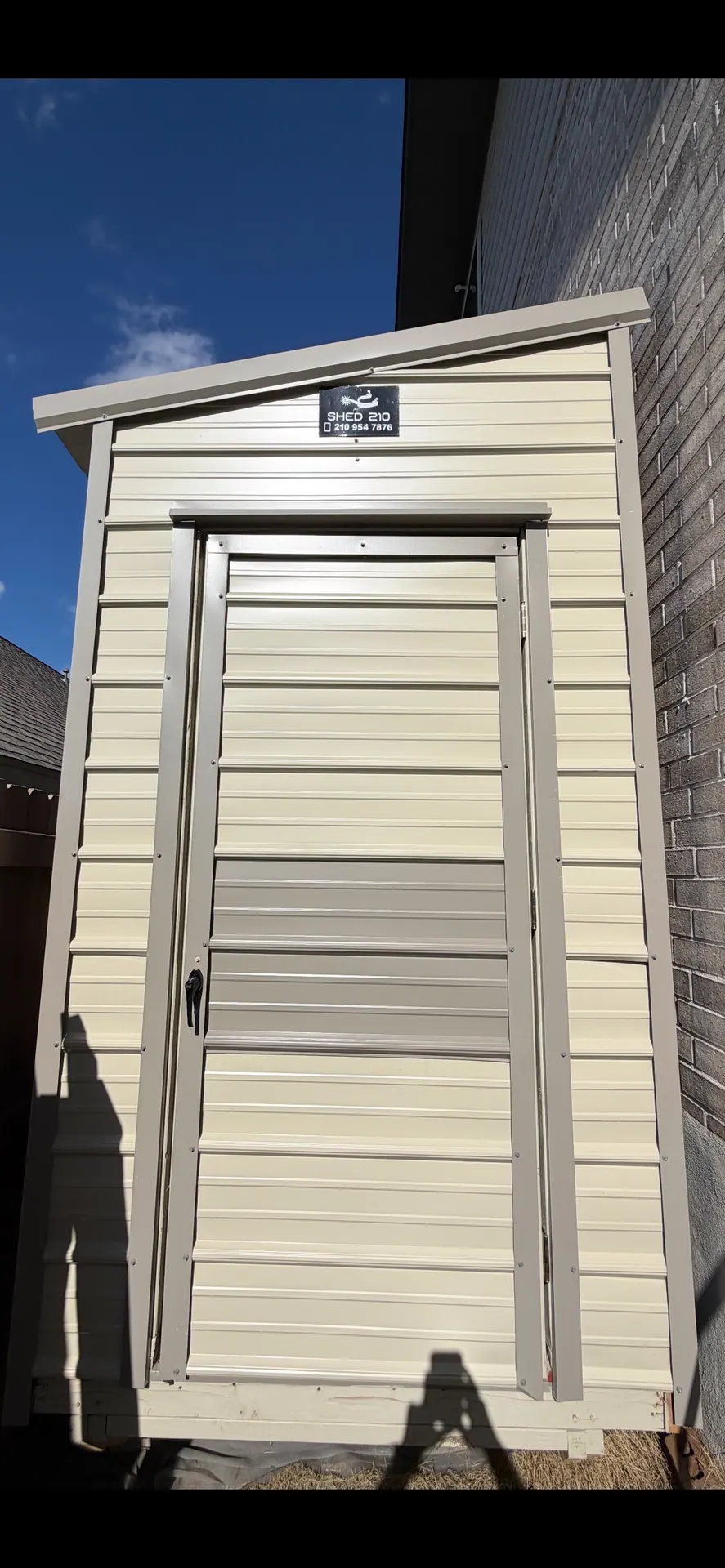Full front view of the 6x16x9 Side Utility shed with cream siding, tan trim, and entry door