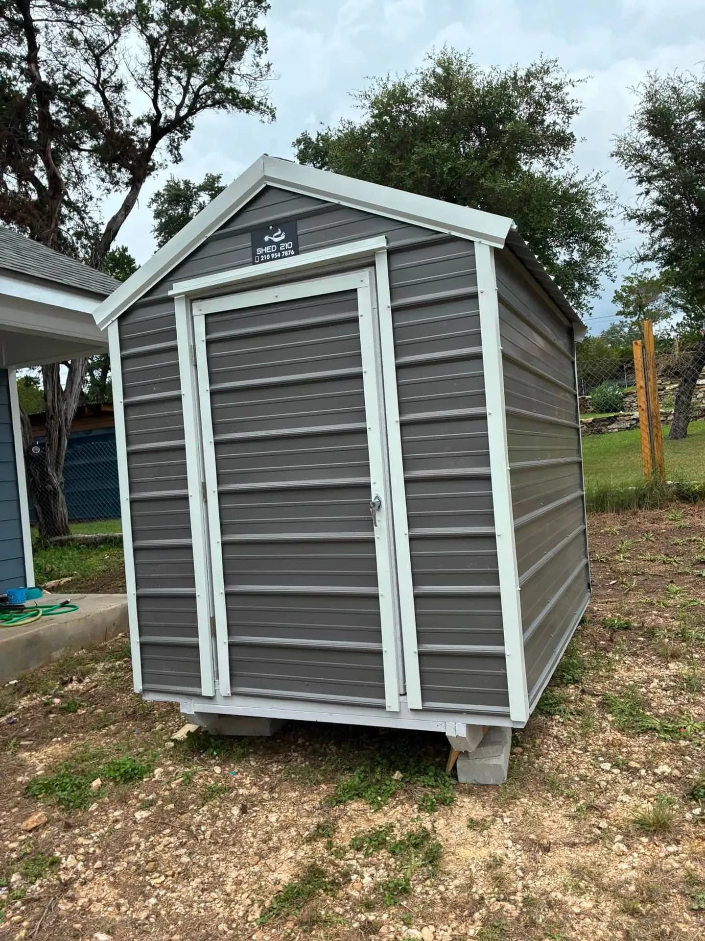 Charcoal 6x8x7 metal shed with Alamo White trim and lockable door, custom built on-site by Shed 210 in Lakehills, TX