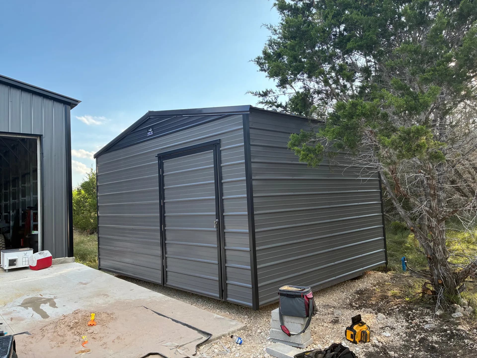 Front and right-side view of the gray metal utility shed and its extra-wide access door