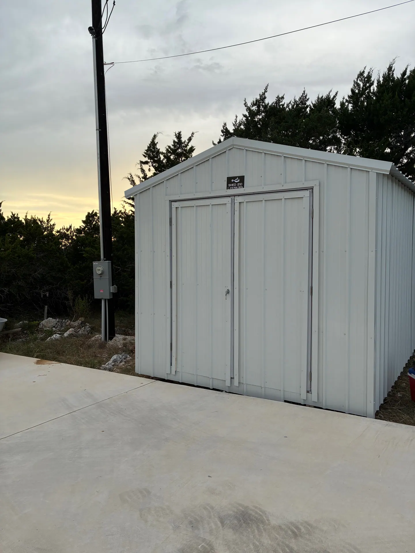 Front three-quarter view of the finished white 10x12x8 storage shed with double doors in Boerne, TX.