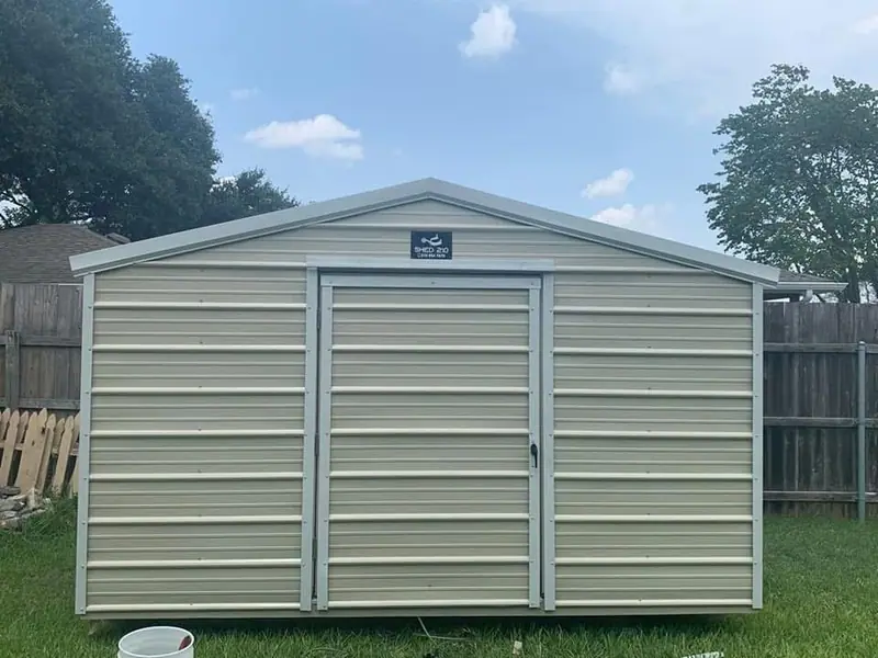 Straight-on view of the completed 8x12x7 Side Utility shed with Light Stone metal siding, white trim, and a closed entry door in Poteet.