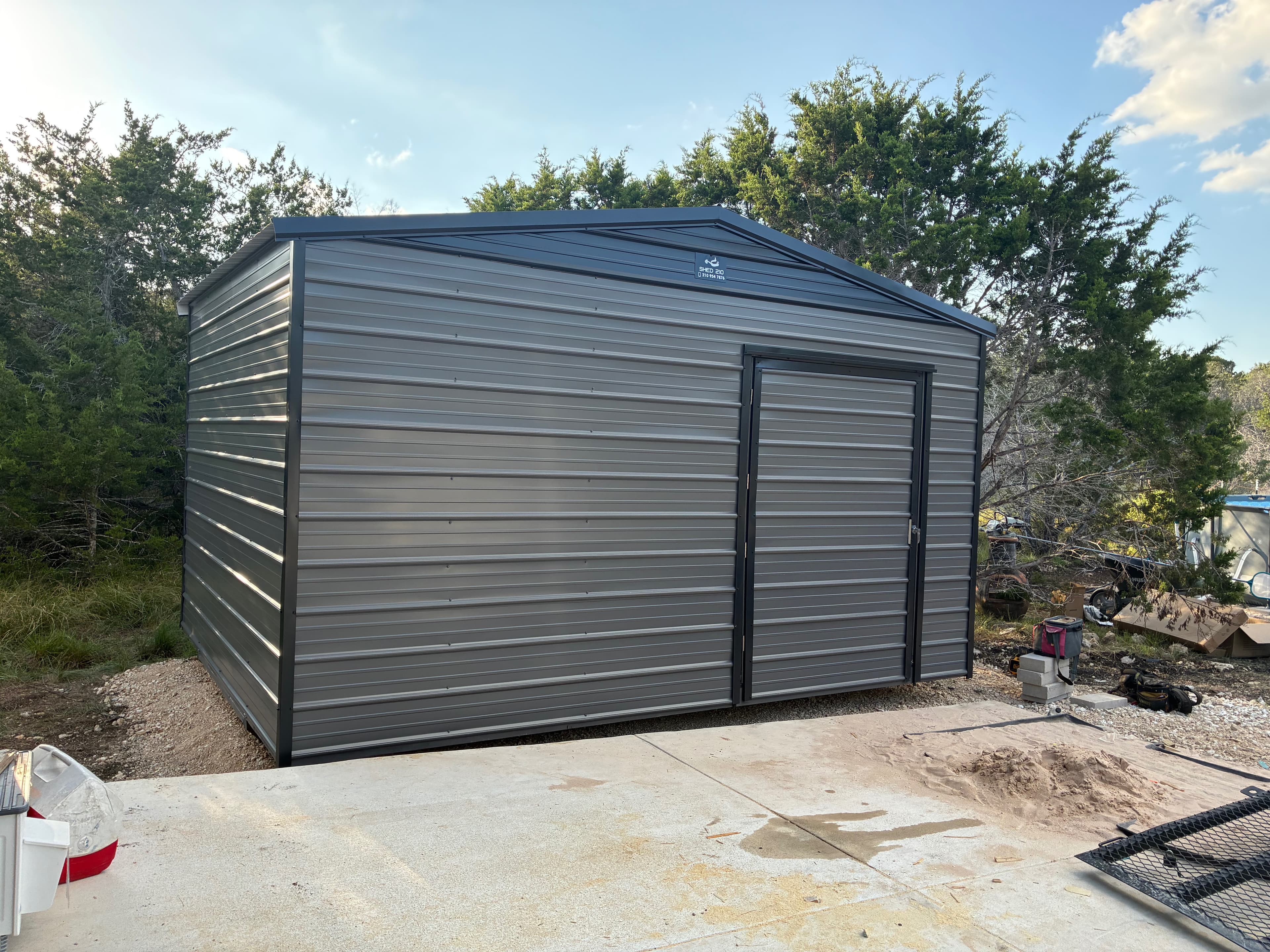 Front three-quarter view of a gray 12x16x9 utility shed with an extra-wide door and dark trim in Boerne, TX
