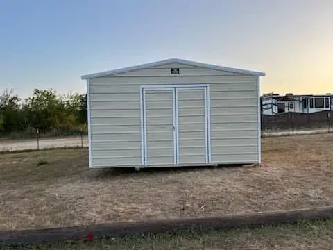 Straight-on view of the completed 16x20x9 Side Utility shed with light tan metal siding, white trim, and closed double doors in Luling.